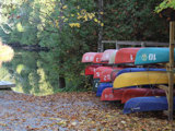 Colourful canoes and kayaks on a stand beside a dock and boat launch along the Indian River at Warsaw Caves Conservation Area.