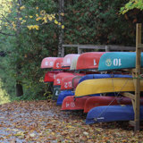 Colourful canoes and kayaks on a stand beside a dock and boat launch along the Indian River at Warsaw Caves Conservation Area.