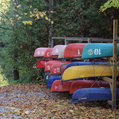 Colourful canoes and kayaks on a stand beside a dock and boat launch along the Indian River at Warsaw Caves Conservation Area.